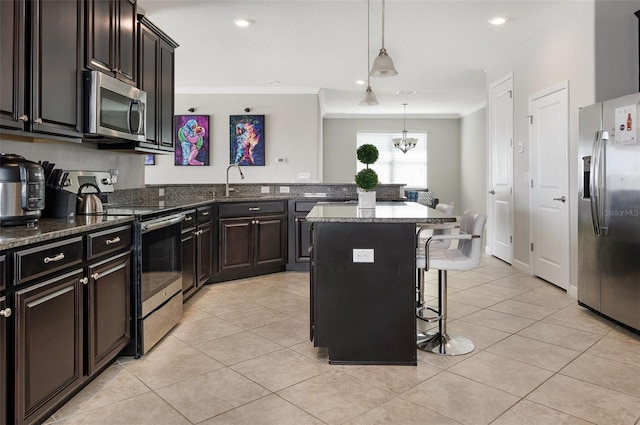 10008 Celtic Ash Dr, Ruskin, FL 33573 - kitchen featuring appliances with stainless steel finishes, ornamental molding, a kitchen breakfast bar, light tile patterned flooring, and dark stone counters