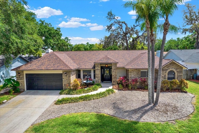 single story home featuring brick siding, a shingled roof, and concrete driveway