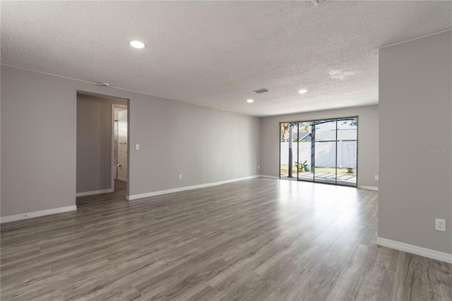 empty room featuring baseboards, a textured ceiling, wood finished floors, and recessed lighting