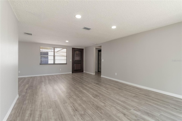 spare room featuring baseboards, visible vents, and light wood-type flooring