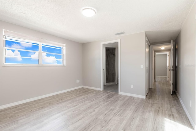 unfurnished bedroom with baseboards, visible vents, light wood-type flooring, and a textured ceiling