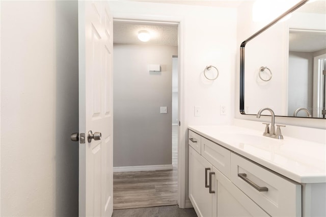 bathroom with vanity, baseboards, and a textured ceiling