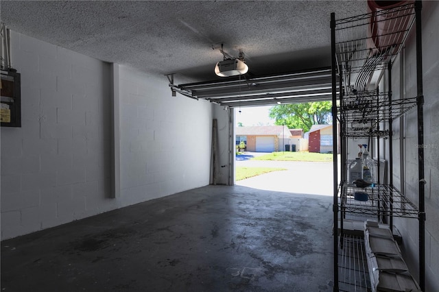 garage featuring a garage door opener and concrete block wall