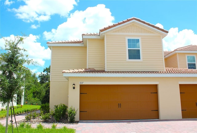 view of front of house featuring a tile roof, stucco siding, and an attached garage