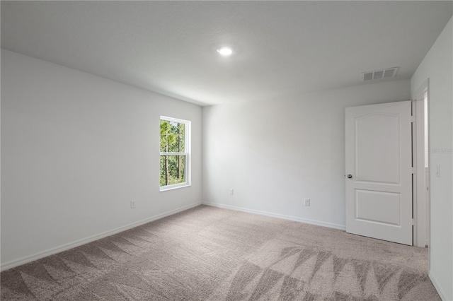 carpeted empty room featuring baseboards and visible vents