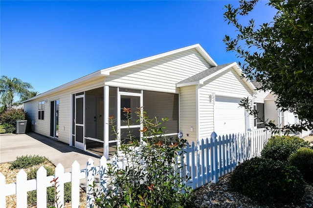 view of front of home with an attached garage, fence, a sunroom, and central air condition unit