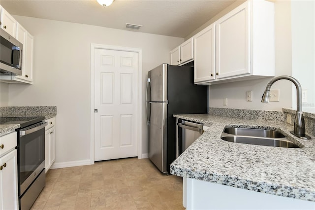 kitchen with white cabinets, visible vents, a sink, light stone countertops, and appliances with stainless steel finishes