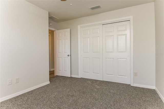 unfurnished bedroom with dark carpet, baseboards, visible vents, and a closet