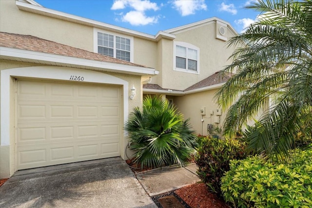 11260 Kapok Grand Cir, Madeira Beach, FL 33708 - view of property with concrete driveway, a garage, and stucco siding