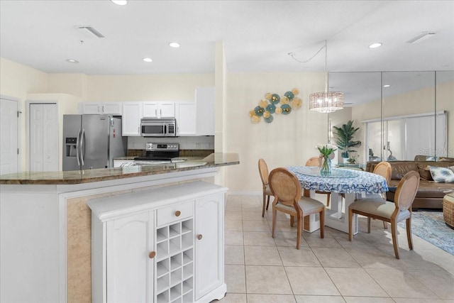 11260 Kapok Grand Cir, Madeira Beach, FL 33708 - kitchen with visible vents, light tile patterned floors, white cabinetry, dark stone counters, and stainless steel appliances