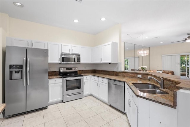 11260 Kapok Grand Cir, Madeira Beach, FL 33708 - kitchen featuring dark stone counters, a sink, white cabinetry, and stainless steel appliances