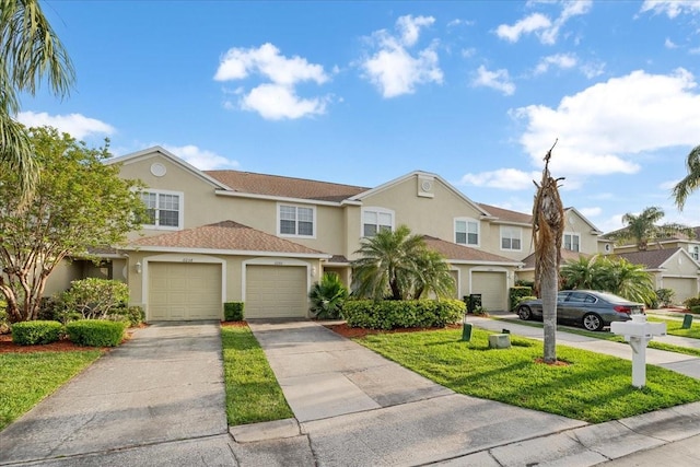 11260 Kapok Grand Cir, Madeira Beach, FL 33708 - townhome / multi-family property with driveway, stucco siding, and a front yard