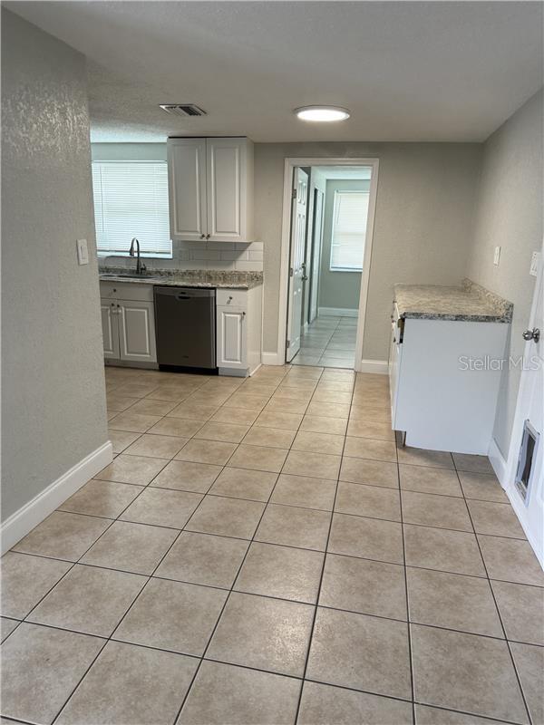 kitchen with light tile patterned floors, baseboards, a sink, visible vents, and dishwashing machine
