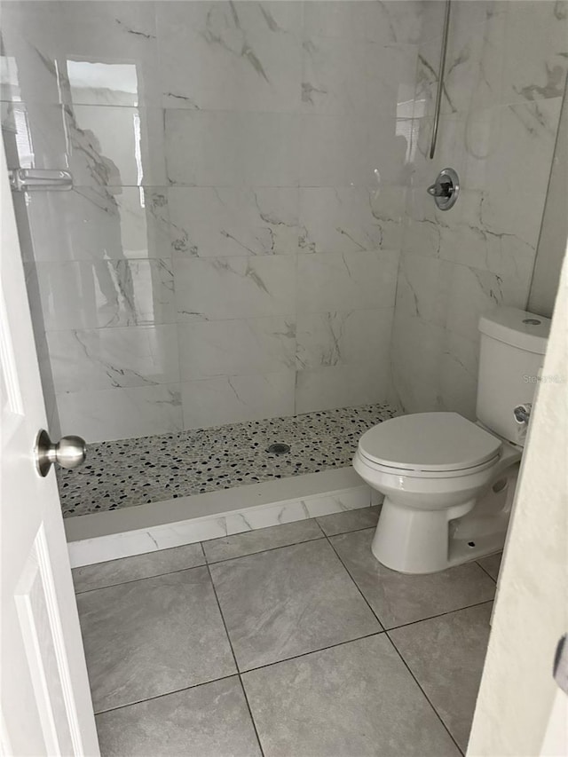 bathroom featuring a marble finish shower and toilet