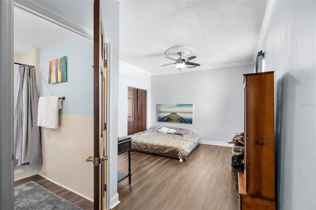 215 Central Ave Unit 4F, Saint Petersburg, FL 33701 - bedroom with crown molding, ceiling fan, a wainscoted wall, wood finished floors, and tile walls
