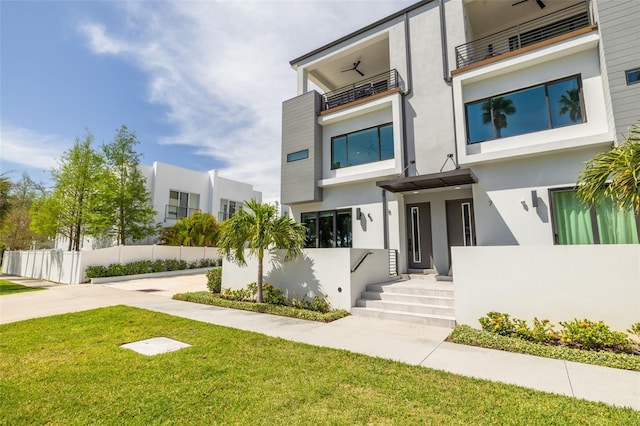 view of front of property with stucco siding, a front lawn, and fence
