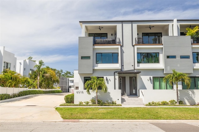 view of front facade with driveway, stucco siding, a front lawn, and a balcony
