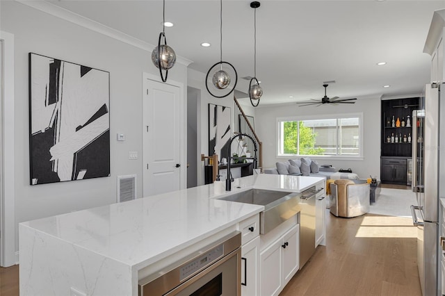 kitchen with ceiling fan, visible vents, a sink, light wood-style floors, and stainless steel appliances