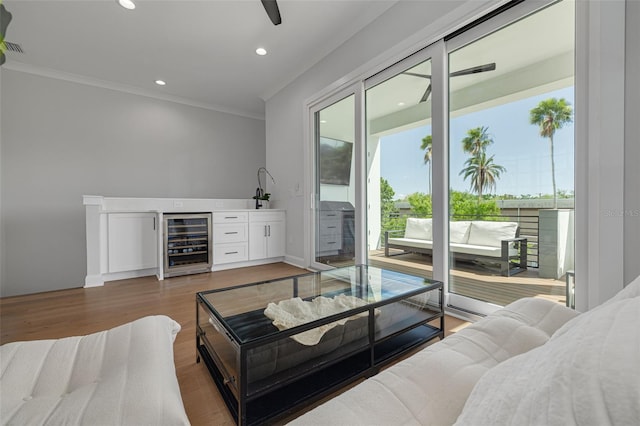living room featuring wine cooler, bar area, recessed lighting, ornamental molding, and wood finished floors