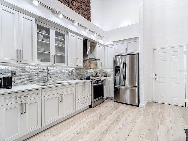 700 S Harbour Island Blvd Unit 143, Tampa, FL 33602 - kitchen featuring light countertops, a towering ceiling, appliances with stainless steel finishes, a sink, and wall chimney range hood