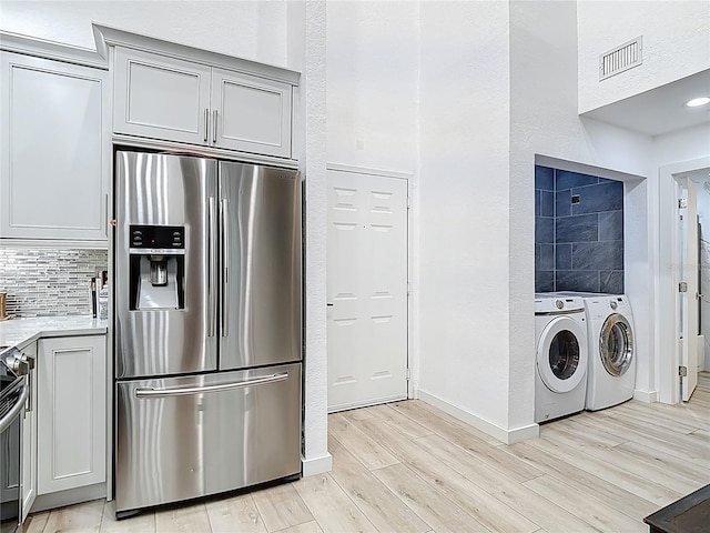 700 S Harbour Island Blvd Unit 143, Tampa, FL 33602 - kitchen with washing machine and dryer, light countertops, light wood finished floors, stainless steel refrigerator with ice dispenser, and visible vents