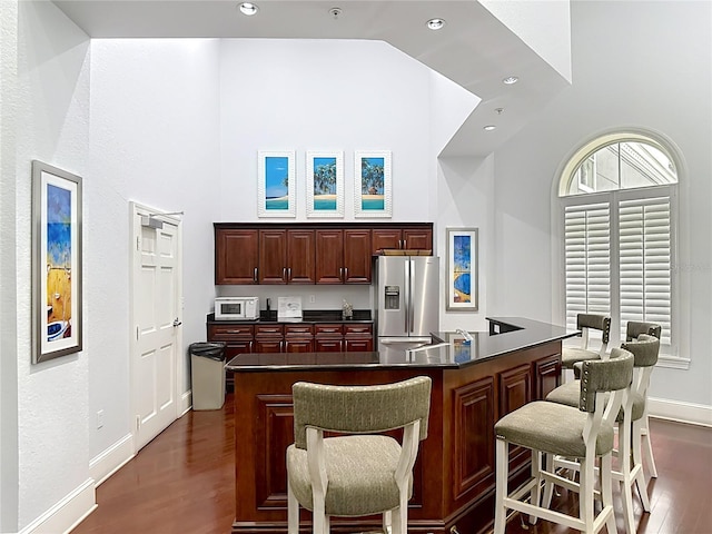 700 S Harbour Island Blvd Unit 143, Tampa, FL 33602 - kitchen featuring high vaulted ceiling, dark wood-style floors, stainless steel refrigerator with ice dispenser, dark countertops, and white microwave