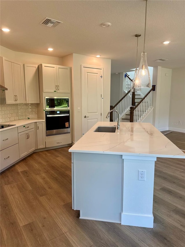 3319 Guanabana Xing, Wesley Chapel, FL 33543 - kitchen featuring appliances with stainless steel finishes, dark wood-style floors, recessed lighting, light stone counters, and hanging light fixtures