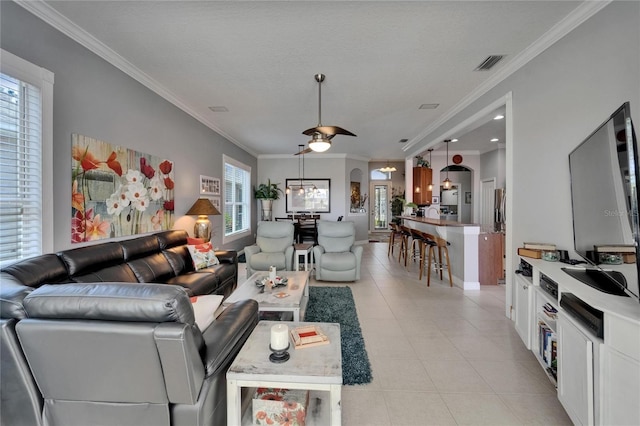 1102 Emerald Dunes Dr, Sun City Center, FL 33573 - living area with light tile patterned floors, crown molding, visible vents, ceiling fan, and arched walkways