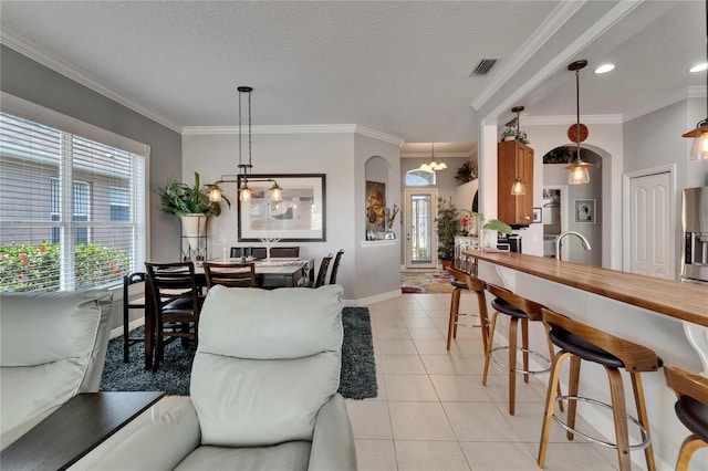 1102 Emerald Dunes Dr, Sun City Center, FL 33573 - living area featuring arched walkways, light tile patterned floors, and crown molding