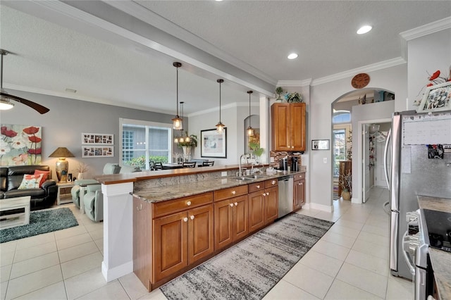 1102 Emerald Dunes Dr, Sun City Center, FL 33573 - kitchen with arched walkways, brown cabinets, light tile patterned flooring, and stainless steel appliances