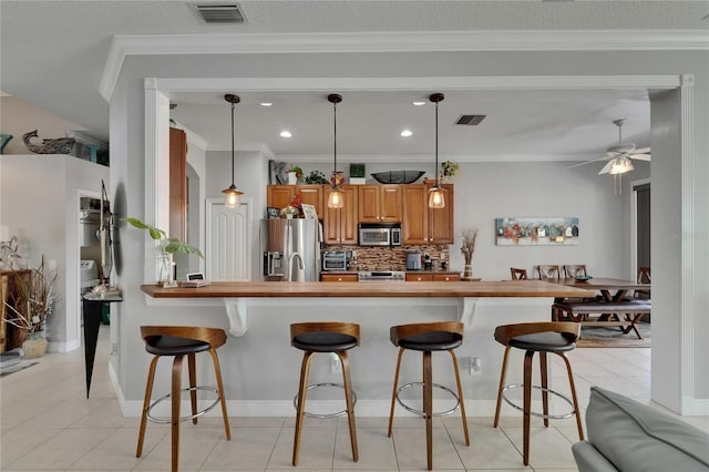 1102 Emerald Dunes Dr, Sun City Center, FL 33573 - kitchen with wooden counters, a kitchen breakfast bar, visible vents, and stainless steel appliances