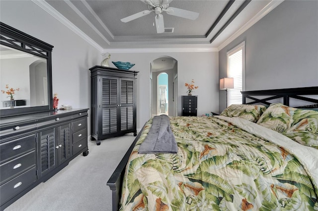 1102 Emerald Dunes Dr, Sun City Center, FL 33573 - bedroom featuring ceiling fan, a tray ceiling, arched walkways, ornamental molding, and light carpet