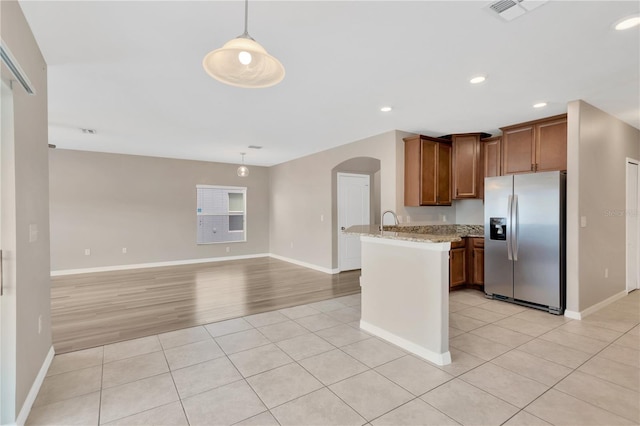 kitchen with stainless steel fridge with ice dispenser, light tile patterned floors, arched walkways, a peninsula, and visible vents