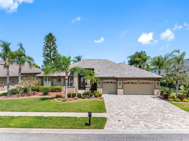 ranch-style house featuring stone siding, a garage, and stucco siding