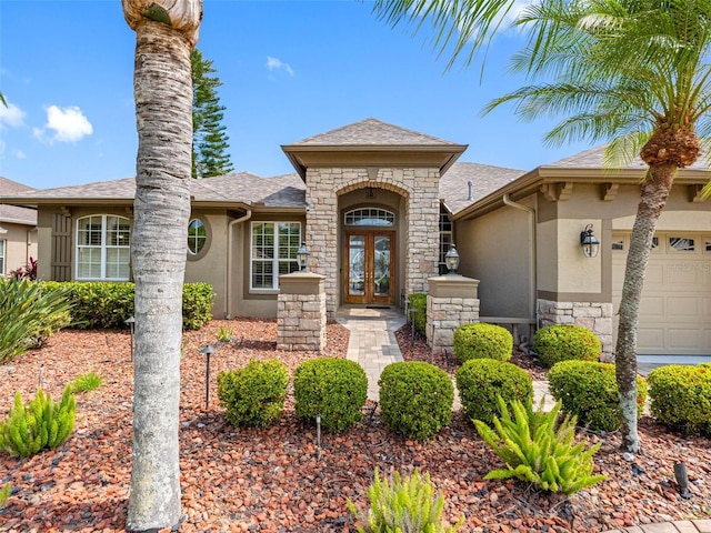 view of front of property featuring french doors, stone siding, stucco siding, and a garage