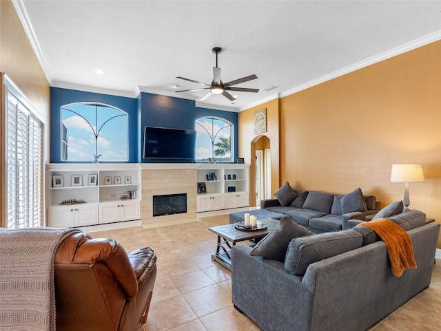 living area featuring a ceiling fan, plenty of natural light, a glass covered fireplace, and light tile patterned flooring