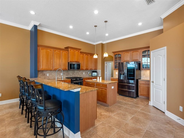 kitchen featuring a peninsula, brown cabinets, a kitchen island, appliances with stainless steel finishes, and glass insert cabinets