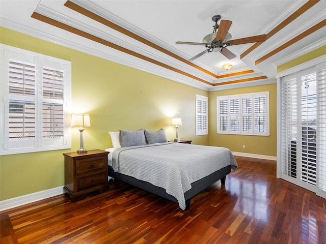 bedroom featuring baseboards, crown molding, wood finished floors, and a raised ceiling