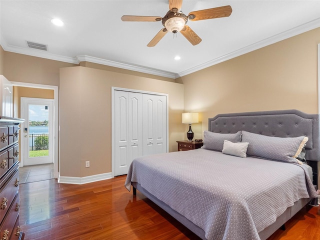 bedroom with a closet, visible vents, baseboards, ornamental molding, and wood finished floors