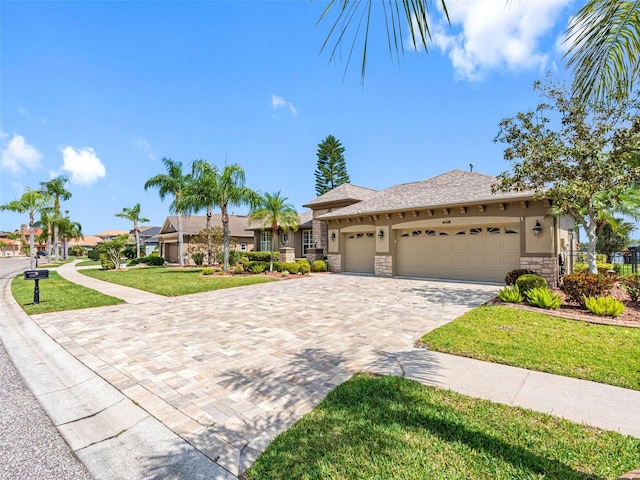 view of front of home featuring stone siding, decorative driveway, an attached garage, a front yard, and stucco siding