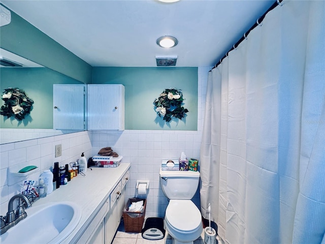 full bath with vanity, tile walls, toilet, a wainscoted wall, and tile patterned floors