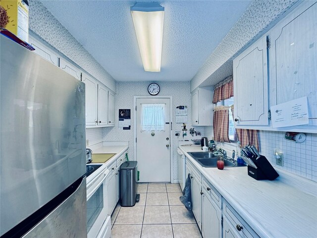kitchen featuring light tile patterned flooring, light countertops, white electric range oven, and freestanding refrigerator