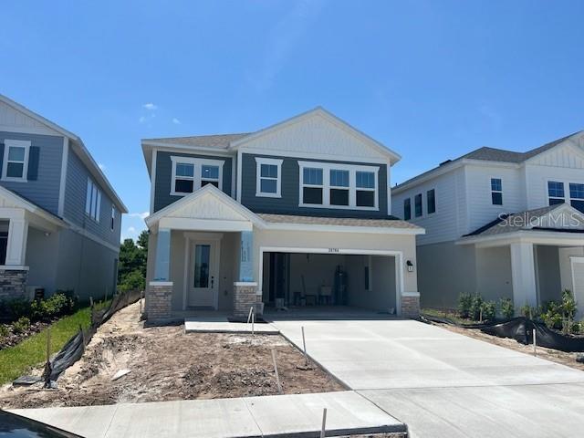 28764 Jujube Rd, Wesley Chapel, FL 33543 - craftsman-style home with concrete driveway, an attached garage, and stone siding