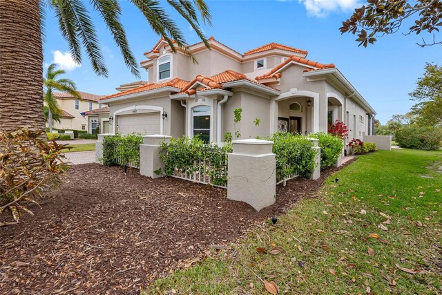 9897 Sago Point Dr, Seminole, FL 33777 - mediterranean / spanish house with driveway, a tiled roof, an attached garage, a front yard, and stucco siding