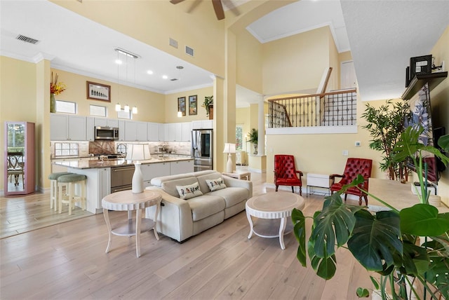 9897 Sago Point Dr, Seminole, FL 33777 - living area with a towering ceiling, ornamental molding, and light wood-style floors