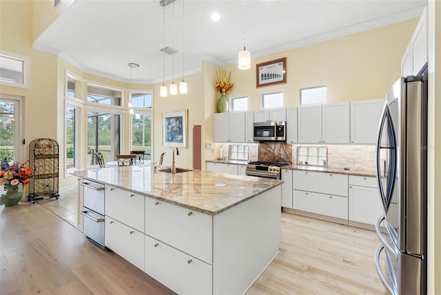 9897 Sago Point Dr, Seminole, FL 33777 - kitchen with white cabinetry, tasteful backsplash, ornamental molding, a sink, and appliances with stainless steel finishes