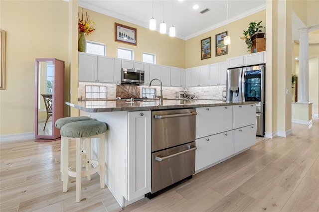 9897 Sago Point Dr, Seminole, FL 33777 - kitchen featuring appliances with stainless steel finishes, a large island, a towering ceiling, ornamental molding, and ornate columns