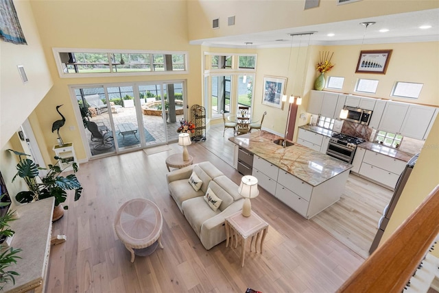 9897 Sago Point Dr, Seminole, FL 33777 - living area with a towering ceiling, baseboards, recessed lighting, and light wood-type flooring