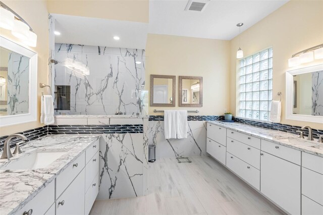 9897 Sago Point Dr, Seminole, FL 33777 - bathroom featuring tile walls, visible vents, a sink, and two vanities