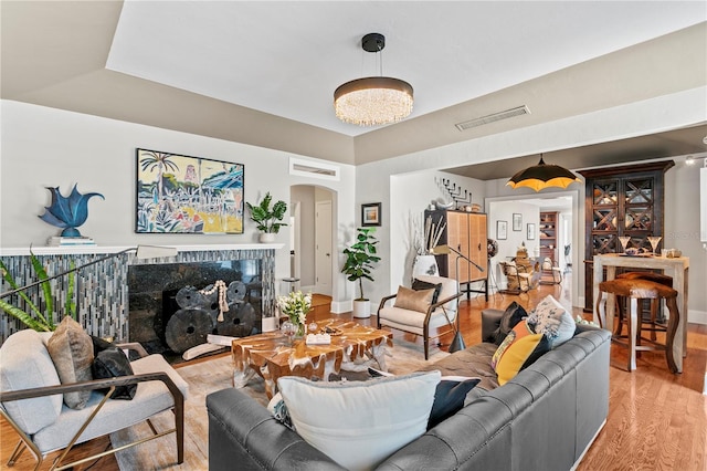 living area with arched walkways, a fireplace, visible vents, and wood finished floors